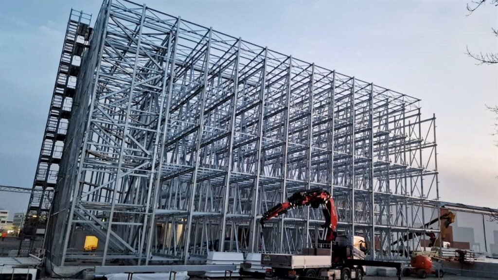 Steel structure framework of a commercial building under construction with cranes and equipment on site.